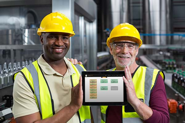 Smiling Factory Workers Holding a Tablet